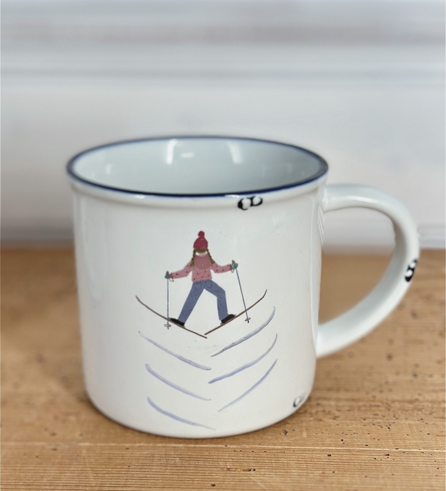 Keramiktasse im Emaille- Look mit einer Schifahrerin im Grätschschritt